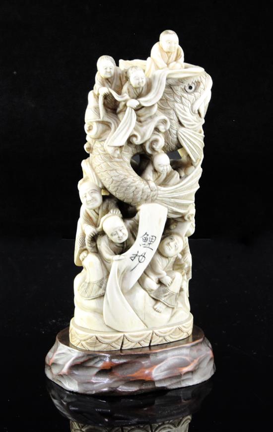 A Japanese walrus ivory okimono of men holding a giant carp, early 20th century, 15cm, wood stand